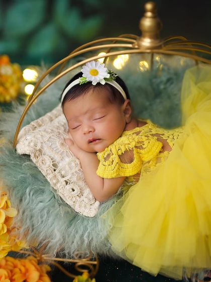 A close-up of the baby in her yellow tulle dress, wearing a sweet daisy headband for her sunny-themed photoshoot.