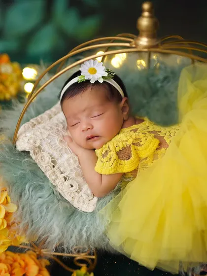 A close-up of the baby in her yellow tulle dress, wearing a sweet daisy headband for her sunny-themed photoshoot.