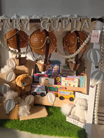 Up, up, and away! This whimsical hot air balloon themed gift includes a personalized bookshelf filled with classic stories and toys, designed to spark a lifetime of imagination for Baby Gupta.