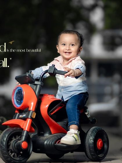 Childhood is the most beautiful season of all. A happy toddler enjoys a ride on his red toy motorcycle.