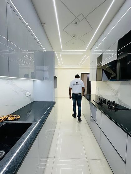 A full view of the completed grey modular kitchen, showcasing the parallel layout and the effective use of profile lighting in the false ceiling.
