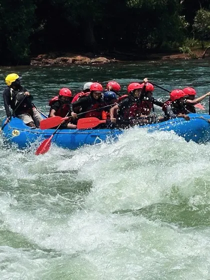 A team of young rafters guided by an instructor paddles through a wave, learning how to handle the raft in turbulent water.