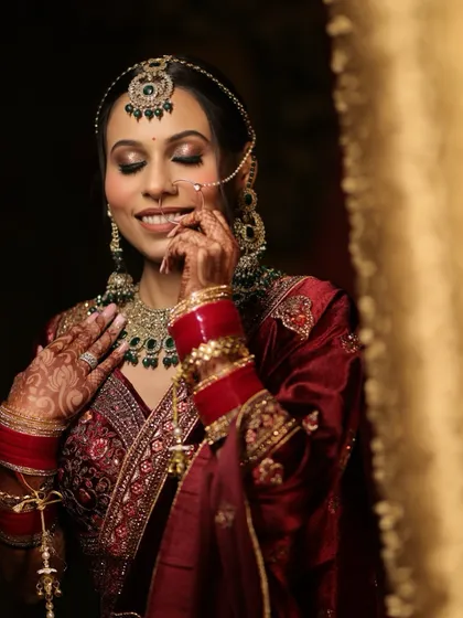 A moment of quiet joy for this beautiful bride. Her makeup features a soft smokey eye and a neutral lip, allowing her natural beauty and stunning velvet lehenga to take center stage.