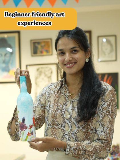 A participant holds up her finished decoupage bottle. The workshop is perfect for beginners and a great way to learn about upcycling.