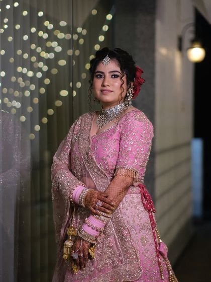 A full-length portrait showcasing the bride's stunning pink lehenga and traditional jewelry, capturing her elegance from head to toe.