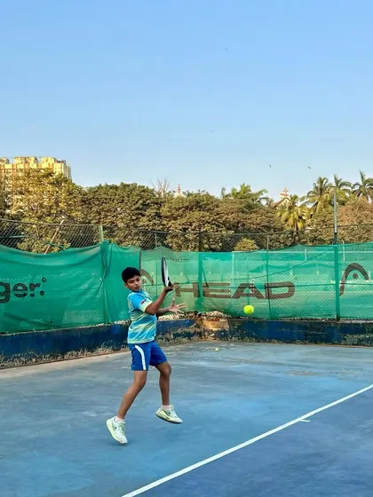 A young player mid-forehand swing, showing great form and concentration during a practice session.