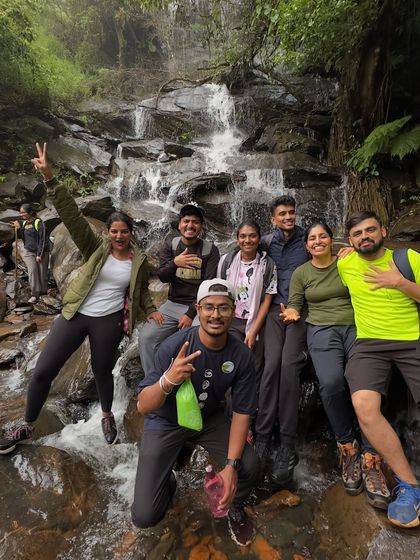 A group of friends taking a break by a small waterfall on the Netravathi trail.