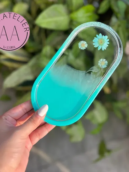 A cool turquoise oval trinket tray. The way the color blends into the clear resin with flowers creates a beautiful ocean-like effect.