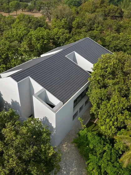 An aerial view of the Mango Orchard House shows how we integrate architecture into the landscape. The monolithic form is carefully positioned within a mature orchard, with the building's layout designed to preserve every existing tree and create a harmonious relationship with nature.