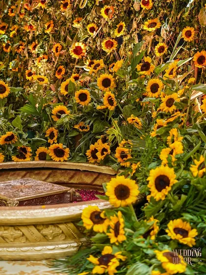 Another angle of the Haldi seating area, surrounded by a dense arrangement of bright yellow sunflowers. The intricate carving on the vessel adds a touch of traditional craftsmanship.