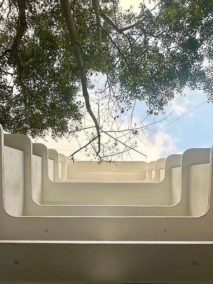 An upward-looking view of an upcoming project in Santacruz, Mumbai. The image focuses on the clean, curved lines of the balconies, showcasing the meticulous detail and form-making that defines the building's architectural character.