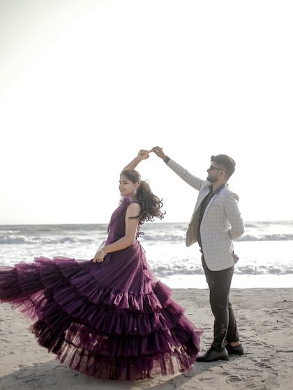 A joyful "dancing on the beach" shot. The twirling motion shows off the beautiful layers of this purple ruffled gown.
