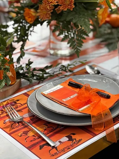 A close-up of the custom placemat and personalized stationery, showcasing the Hermès-inspired horse-and-carriage motif that was woven throughout the event's design.