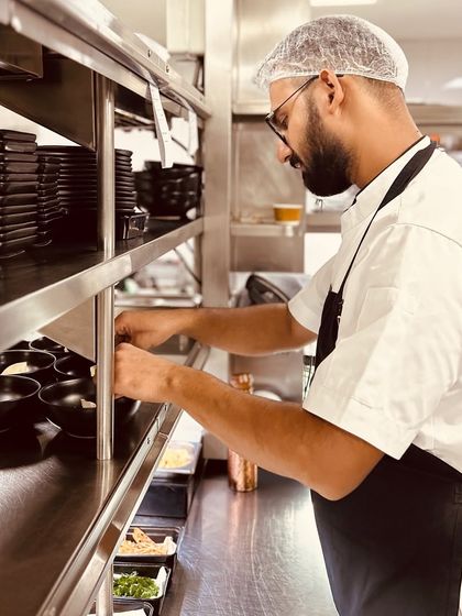 A member of our kitchen team at his station, surrounded by meticulously prepared ingredients. Organization and preparation are key to a smooth service.
