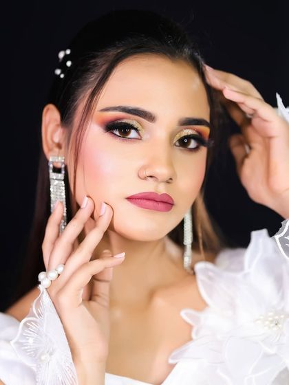 A soft and angelic glamour look, featuring a white outfit, sunset-toned eyeshadow, and sparkling earrings.