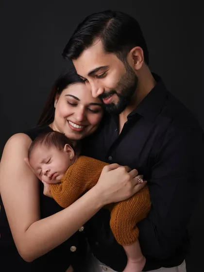 Wrapped in their parents' love. This close-up shot shows the tenderness and protection surrounding a new baby. It's a beautiful way to remember the beginning of your journey as a family of three.