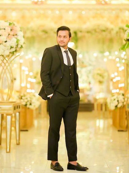 A full-length shot of a client in a classic black suit at a beautifully decorated wedding venue. My grooming service ensures he looks just as elegant as his surroundings.