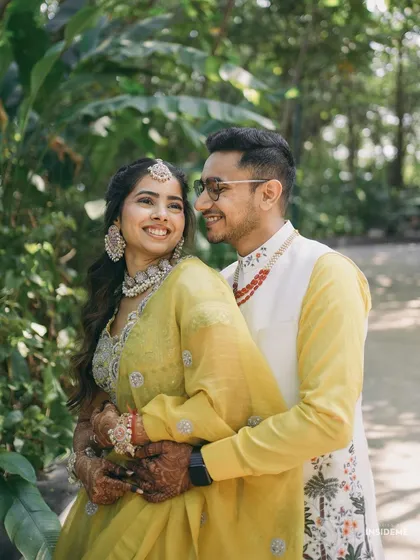 A joyful close-up of the couple. You can see the details of the bride's Haldi makeup, with soft eyeshadow and a natural lip color that enhances her beautiful smile.