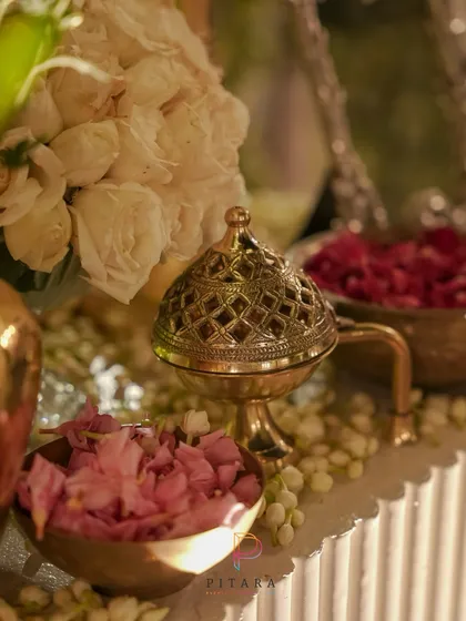 A close-up of a vintage brass incense burner, surrounded by bowls of fresh rose petals and fragrant jasmine. These traditional elements add a sensory layer to the decor, creating a truly immersive experience.