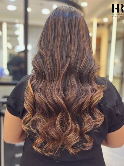 We specialize in creating gorgeous, voluminous waves. This look was achieved with expert styling to enhance the hair's natural texture and the beautiful dimension from the balayage highlights.