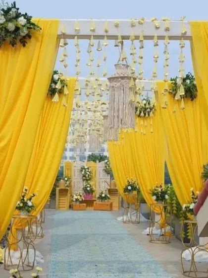 This is the entrance to a vibrant Haldi ceremony I decorated on a rooftop in Lodha. The bright yellow drapes, hanging floral strings, and fresh flower arrangements create a welcoming and festive atmosphere for the celebration.