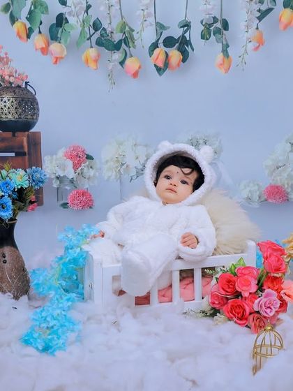 This baby is sitting peacefully in our dreamy floral and snow-themed setup. The combination of soft clouds and hanging flowers creates a magical atmosphere.