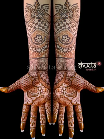 An intricate and dense bridal mehendi design. The pattern is filled with floral motifs, checks, and swirls, creating a rich and luxurious look for the bride's hands.