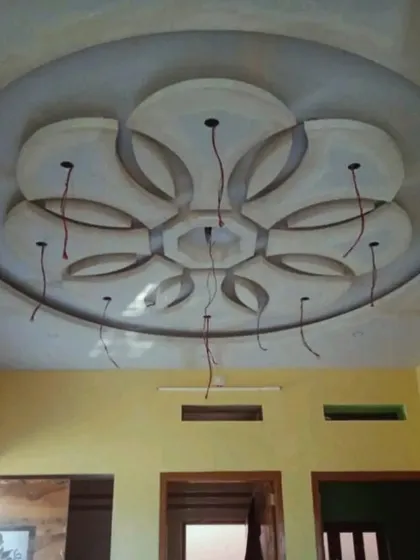 An in-progress view of an intricate floral medallion design for a ceiling centerpiece. This shows the raw POP and gypsum work before the final finishing and painting, highlighting the detailed craftsmanship.
