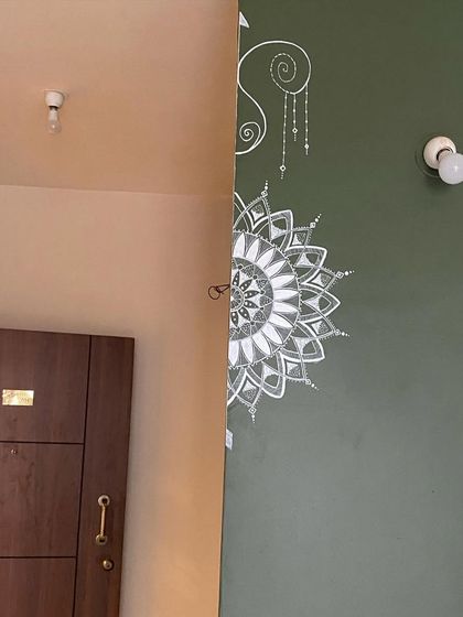 This semi-mandala was uniquely designed to wrap around a corner. The intricate white details on the olive green wall create a beautiful and continuous piece of art that flows from one space to another.