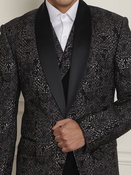 A close-up of a black and silver patterned tuxedo jacket. This is for the man who wants his formal wear to have a touch of glamour and personality.