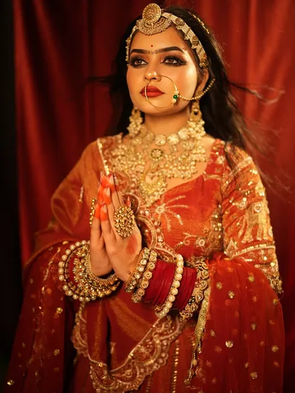 A Padmavat-inspired look, with the bride in a prayer pose. The makeup is strong and traditional.