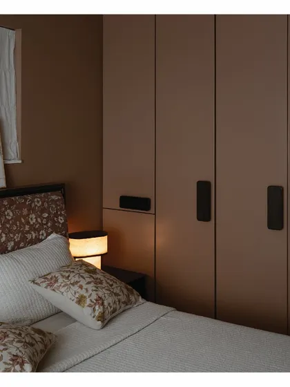 A closer look at the desert-toned master bedroom in our home. The mauve wardrobes feature bespoke emerald-toned handles, and the headboard is upholstered in a delicate floral fabric. These custom details and warm colors make the space feel uber-dusky and cozy.