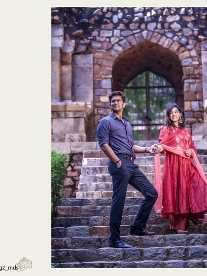 The historic architecture of Delhi's monuments provides a timeless setting for pre-wedding photography. This shot uses the stone archways to frame the couple perfectly.
