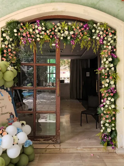 An elegant floral archway I created for the entrance of Anaya's baby shower. The mix of pink, purple, and white flowers with green foliage provides a warm welcome for guests.