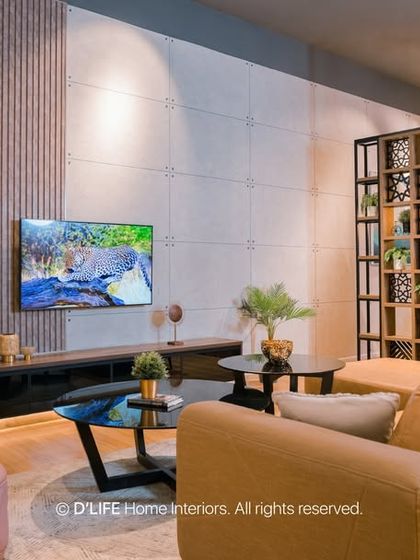 A cozy living room setting with a comfortable sofa, a soft pink armchair, and a textured wall with integrated lighting. The space is defined by its warm and inviting atmosphere.