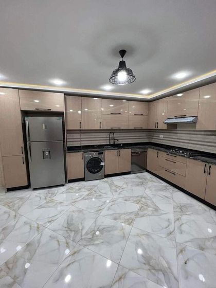 This spacious L-shaped kitchen combines beige cabinetry with black granite countertops for a warm, contemporary look. The design includes ample storage and counter space, with a layout that is perfect for an open-plan home.