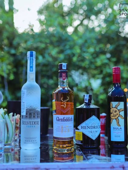 A well-stocked bar at an outdoor birthday party, featuring a selection of premium spirits like Belvedere, Glenfiddich, and Hendrick's Gin.