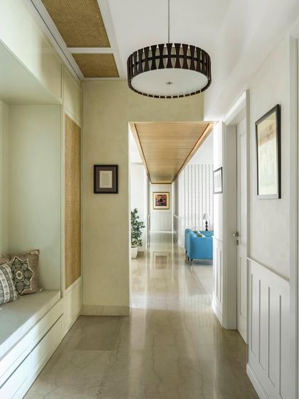 This corridor from "The Ivy Nest" project features a built-in bench with storage, paneled walls, and a statement drum pendant light, turning a simple passageway into a functional and beautifully designed space.