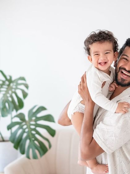 A father and son portrait filled with laughter. The bright, high-key lighting matches the joyful mood.