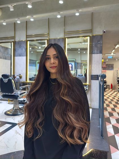 A front view of this stunning balayage, showing how the lighter pieces frame the face and brighten the overall look. The long, flowing layers are styled into waves to showcase the color's dimension.