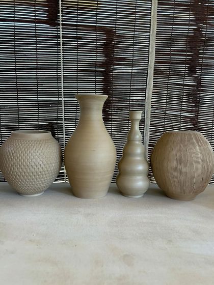 A collection of large, unglazed vases in various shapes and sizes. Each one is thrown on the wheel and showcases a different form, from classic curves to textured surfaces.