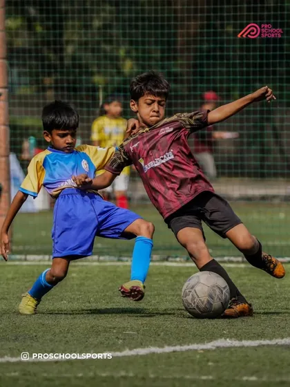 A great action shot of a young player making a strong tackle to win the ball.