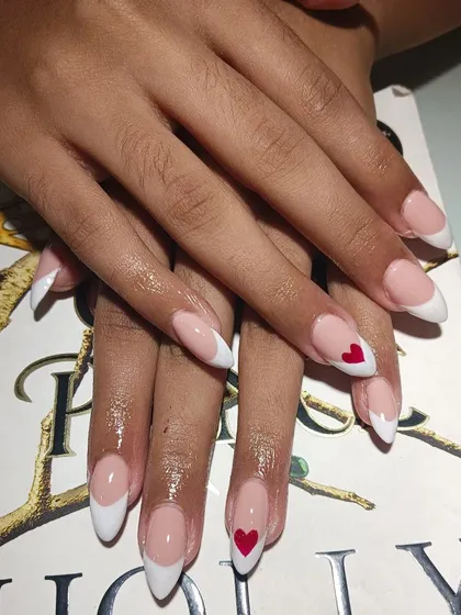 A cute twist on a timeless classic. This is a sharp, white French manicure on almond-shaped extensions, with a tiny, hand-painted red heart accent nail. It’s a simple detail that adds so much personality.