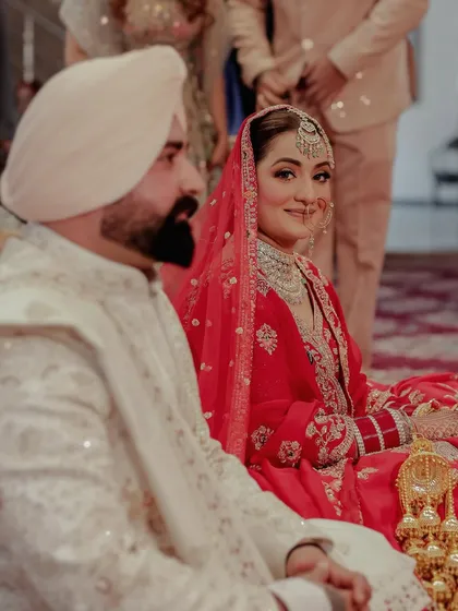 During the wedding ceremony, it's the small, knowing glances that often mean the most. This candid shot captures the bride's gentle smile during the Anand Karaj, a quiet moment of happiness that we specialize in preserving.