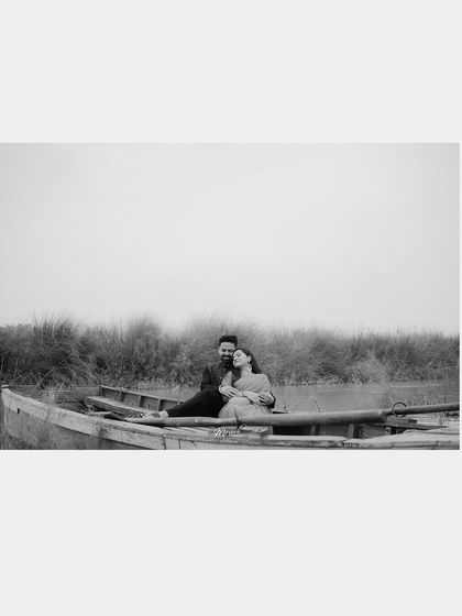 A wide-angle, minimalist composition in black and white, placing the couple's connection at the center of the vast, quiet landscape.