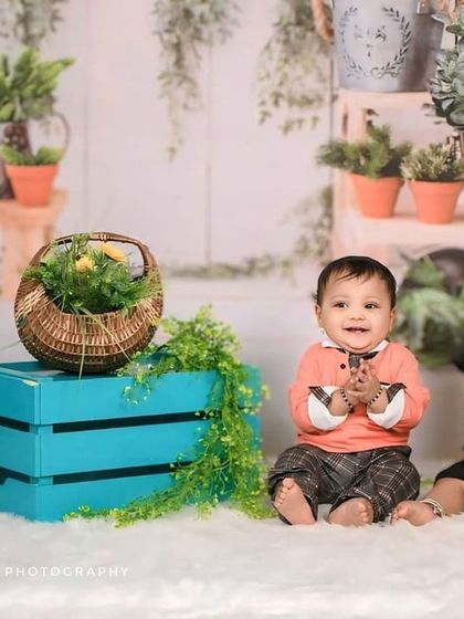 Another charming shot of twin babies in a garden-themed studio setup. Their happy expressions and playful clapping make this a joyful and heartwarming sibling portrait.