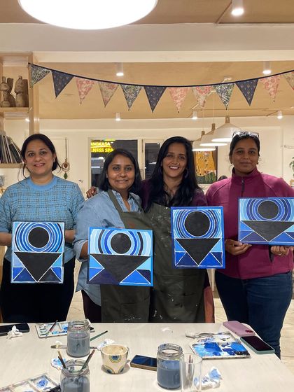 A group of friends proudly holding up their geometric abstract paintings, all with a similar theme but unique personal touches.