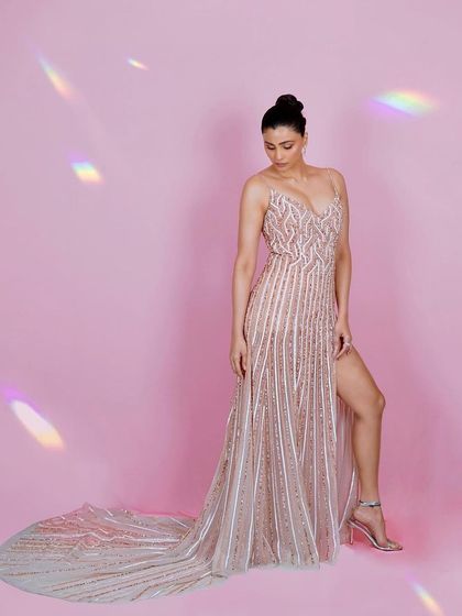 A graceful shot of Daisy Shah looking down, highlighting the delicate straps and intricate beadwork of her gown. The pose conveys a sense of quiet elegance.