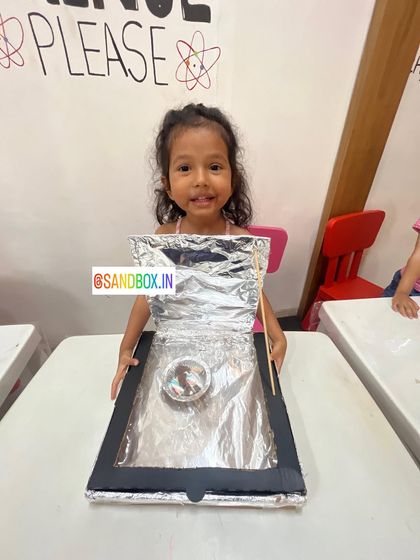 Look at that happy face! She's so proud of the solar cooker she made. It's amazing to see kids realize they can harness the power of the sun with simple materials.