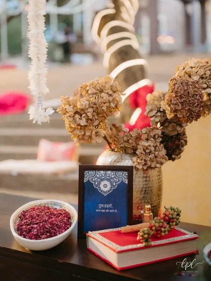 A detail from the Kashmiri Mehfil, featuring a bowl of dried rose petals, fragrant attar, and a framed note in Hindi.